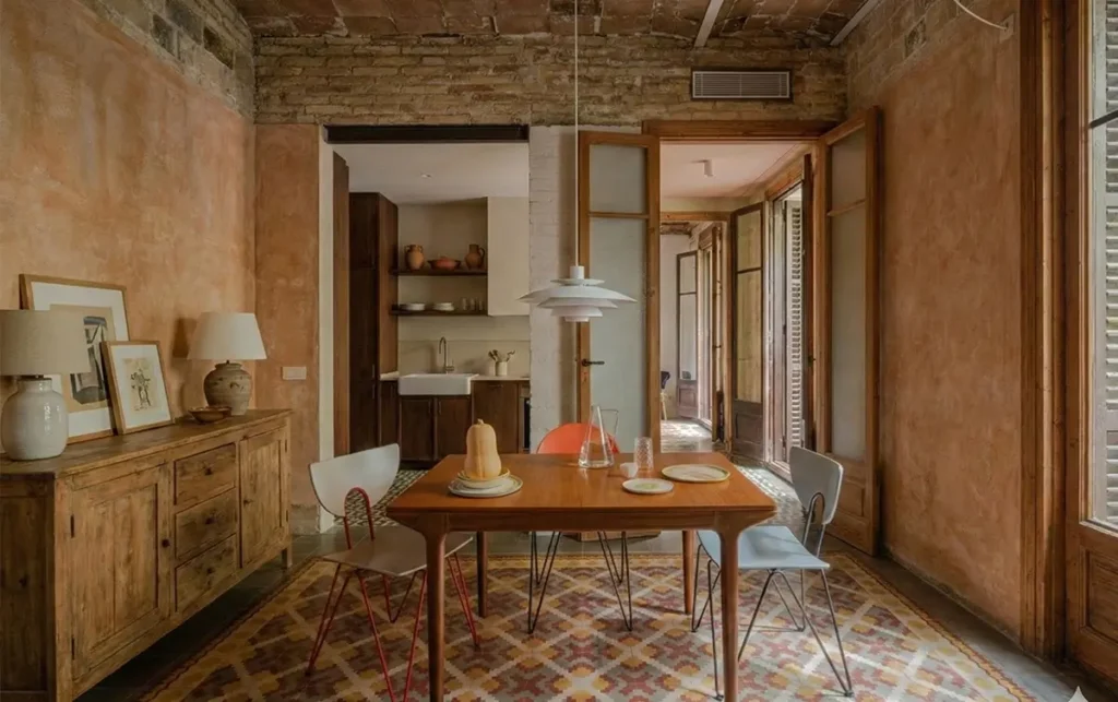 Dining room in a renovated Barcelona apartment with hydraulic tiles Apartment Renovation dining room with hydraulic floor tiles, exposed brick ceiling and wooden-framed doors for expat homeowners