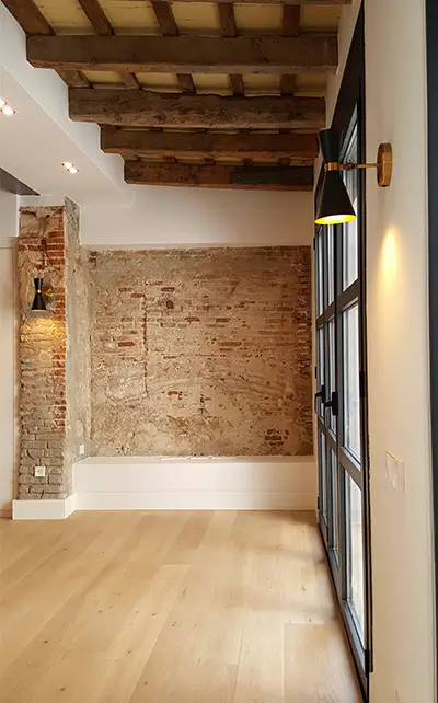 Apartment renovation in Barcelona with exposed brick and wooden beams Apartment Renovation Barcelona with exposed brick feature wall, wooden beams, oak flooring and black-framed windows