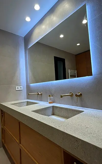 Modern double-sink bathroom remodel in Barcelona Modern bathroom remodel Barcelona with double integrated sink, backlit mirror and brushed brass wall-mounted taps
