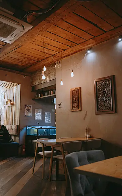 Commercial Renovation Barcelona for a cozy restaurant interior with warm wood ceiling, modern hanging lights and intimate dining tables