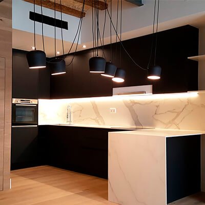 Modern custom kitchen renovation in Barcelona with black cabinets, marble-effect countertop and pendant lighting by Revive Quality