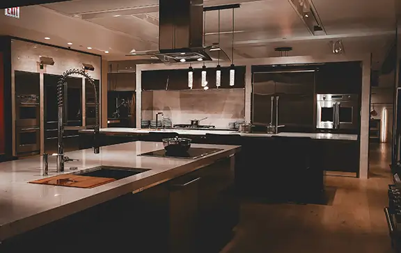 Industrial modern kitchen with large island, stainless steel appliances and pendant lighting in a Barcelona apartment