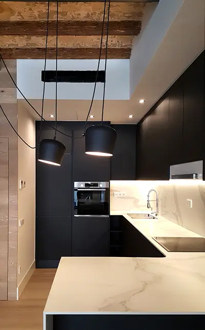 Kitchen Remodel Barcelona with matte black cabinets, marble-look island, exposed wooden beams and modern pendant lighting