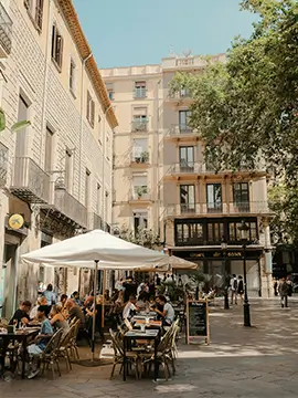 Lively Barcelona square with outdoor café and historic buildings, setting for detailed home renovation services in Barcelona