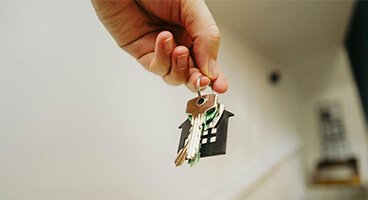 Hand holding house-shaped keyring with keys symbolising turnkey completion of remote home renovation in Barcelona by Revive Quality