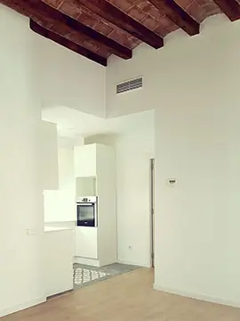 Bright Barcelona kitchen with wooden beam ceiling Renovated Barcelona apartment with white open kitchen, wooden ceiling beams and built-in oven